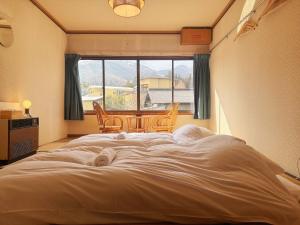 a large bed in a room with a window at Hakuba Hospitality Inn YUKINOSO in Hakuba