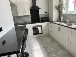 a kitchen with white cabinets and a black stove at At Number 36 in London
