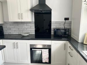 a kitchen with white cabinets and a stove top oven at At Number 36 in London +29 photos