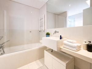 a white bathroom with a sink and a tub and a mirror at Bom dia Parque Nações LisboaX in Lisbon