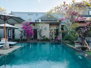 a swimming pool in front of a house with flowers at Ashana Hotel in Uluwatu +30 photos