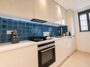a kitchen with white cabinets and blue tile on the wall at Bom dia Parque Nações LisboaX in Lisbon +28 photos