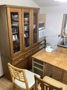 a kitchen with a wooden cabinet and a table and chairs at 心のふれあい民泊 in Shimanto