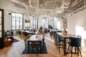 a dining room with tables and chairs and windows at Ruby Hanna Hotel Stuttgart by IHG in Stuttgart