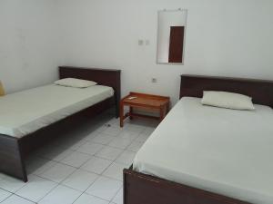a room with two beds and a night stand at Hotel Puma Bungalow in Huu