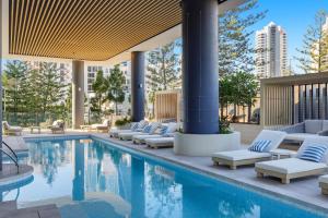 a pool with lounge chairs next to a building at Amaya in Gold Coast
