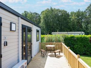 a deck with a table and a bench on a house at Charming caravan with terrace for 6 in Vierhuizen