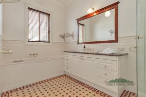a bathroom with a tub and a sink and a mirror at Llewoh on Crofton in Echuca