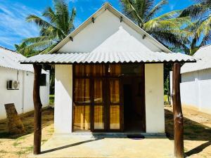 a small white building with a door at Traveller's Home Safari Resort in Udawalawe