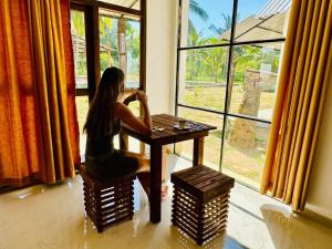 a woman sitting at a table in front of a window at Traveller's Home Safari Resort in Udawalawe