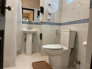a white bathroom with a toilet and a sink at ROKPA Guest House in Kathmandu