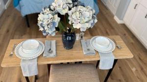 a table with plates and a vase of flowers on it at Stylish Studio in Oleander Close to Downtown in Bakersfield