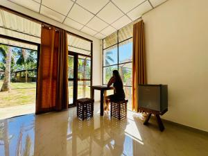 a woman sitting at a table in a room with a tv at Traveller's Home Safari Resort in Udawalawe