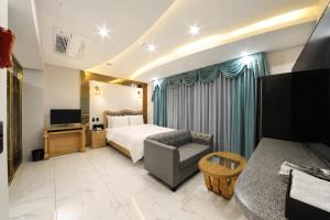 a bedroom with a bed and a couch and a television at Hotel Felice Dongchon Amusement park in Daegu