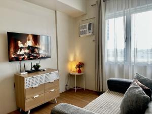 a living room with a couch and a flat screen tv at 8F Cozy 1-Bedroom Unit The Loop Towers in Cagayan de Oro