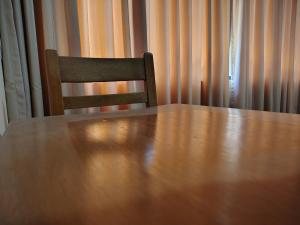 a wooden table and a chair in front of a curtain at Hotel Las Viñas in Huánuco