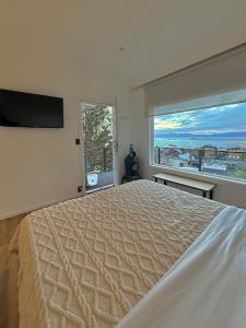 a bedroom with a large bed and a large window at Balcón Austral beautiful apartment with incredible views of the mountains and the city in Ushuaia