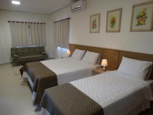 a hotel room with two beds and a chair at Hotel e Restaurante Sabor de Minas in Salinas +28 photos