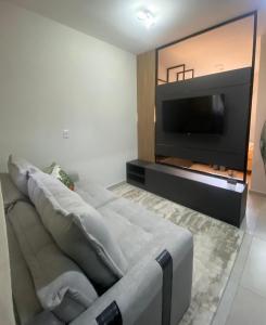 a living room with a couch and a flat screen tv at Studios Carambeí in Carambeí