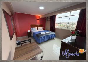 a bedroom with a bed and a table and a window at Hostal Mineola Huacho in Santa María