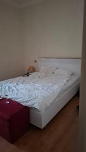 an unmade bed with white sheets and a red suitcase at The Golden Street Hotel in Baku