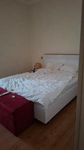 an unmade bed with white sheets and a red suitcase at The Golden Street Hotel in Baku