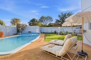 a swimming pool with two lounge chairs and an umbrella at Mediterranean Beachside retreat with a pool in Broadwater