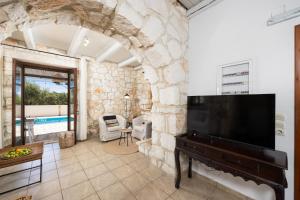 a living room with a piano and a stone wall at Villa Boscheto Tria in Agios Leon