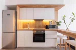 a kitchen with white cabinets and a stainless steel refrigerator at Skg Cityscape Metropolis in Thessaloniki +35 photos