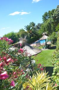 a garden with tables and chairs and flowers at Hotel Carmen de Areco in Carmen de Areco