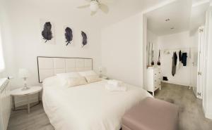 una camera da letto bianca con un letto grande e una sedia di Apartamento Turístico la Concordia a Guadalajara
