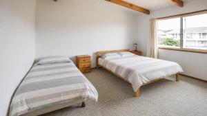 a bedroom with two beds and a window at Summer House On Kurrawa - stunning beach views in Kioloa