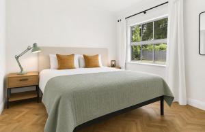 a white bedroom with a large bed and a window at Wood Street Haven in Greytown