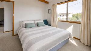 a bedroom with a large bed and a window at Summer House On Kurrawa - stunning beach views in Kioloa