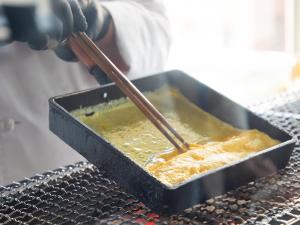 a person is preparing food in a pan with chopsticks at Hotel Resol Hakodate in Hakodate