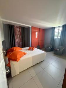 a bedroom with a bed with orange pillows and two toilets at AU BONHEUR DE PINPIN in Les Abymes +10 photos
