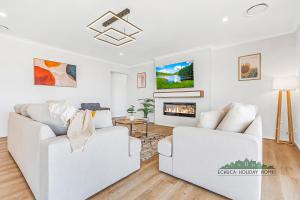 ein Wohnzimmer mit zwei weißen Sofas und einem Kamin in der Unterkunft Riverside Meadows in Echuca