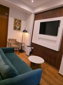a living room with a blue couch and a tv at Alpacaterra Machupichu Hotel in Machu Picchu