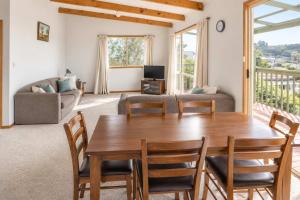 a living room with a wooden table and chairs at Summer House On Kurrawa - stunning beach views in Kioloa