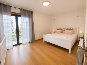 a bedroom with a white bed and a large window at Bom dia Parque Nações LisboaZ in Lisbon