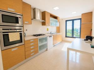 a kitchen with wooden cabinets and a stove top oven at Bom dia Parque Nações LisboaZ in Lisbon