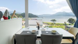 a dining room with a table and chairs and a large window at That Day's Namhae Ocean View Pension in Namhae