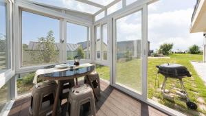a screened in porch with a table and chairs and windows at That Day's Namhae Ocean View Pension in Namhae