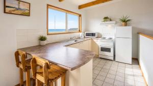 a kitchen with a white refrigerator and a sink at Summer House On Kurrawa - stunning beach views in Kioloa