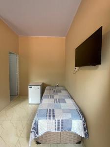 a bedroom with a bed with a flat screen tv on the wall at Casa Dona Vilma in Barreirinhas