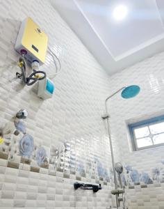 a white tiled bathroom with a shower in a room at Fofana Luxury Suites in Sotuom