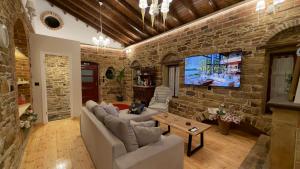 a living room with a brick wall and a tv at Archontiko Chios Traditional Mansion in Thymianá