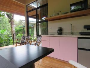 a kitchen with pink cabinets and a balcony at Ruca Lodge -Luxury Cabins Nestled in Nature in Uvita