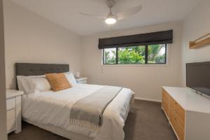 a bedroom with a bed and a flat screen tv at Tahana Villa - River View Retreat - 3 Bedroom in Oakura