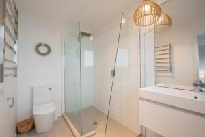a bathroom with a shower and a toilet and a sink at Tahana Villa - River View Retreat - 3 Bedroom in Oakura +25 photos